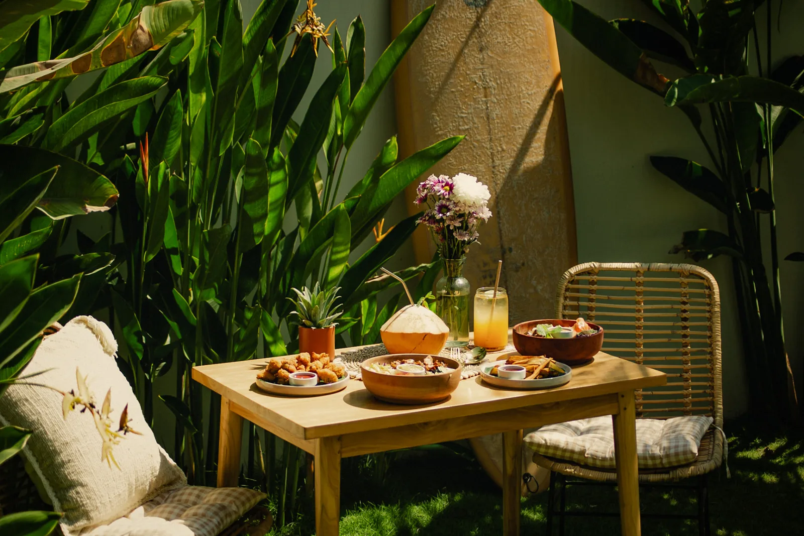 Table set with bowls, fries and a fresh coconut in the garden at Luana Bowls
